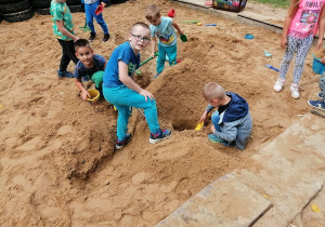Dzieci z grupy biedronki kopią tunele w piaskownicy